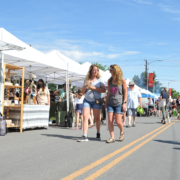 people walking on a street between farmers market stands